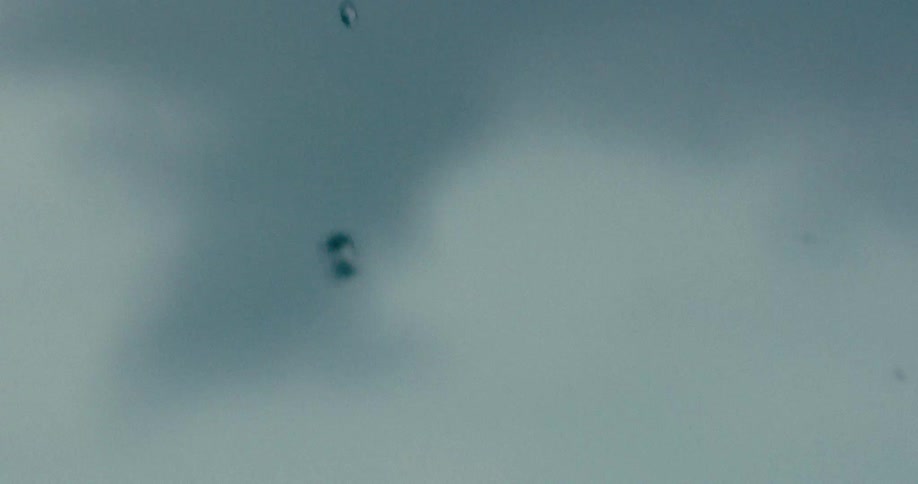 Abstract macro shot of water droplets falling against a blurry blue and grey background