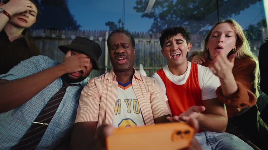 A diverse group of friends react with despair and disappointment in slow motion as they watch their favorite sports team lose on a smartphone