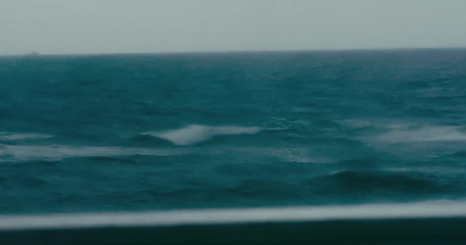 Slow motion footage from a ship shows the turbulent, deep teal ocean during a powerful storm