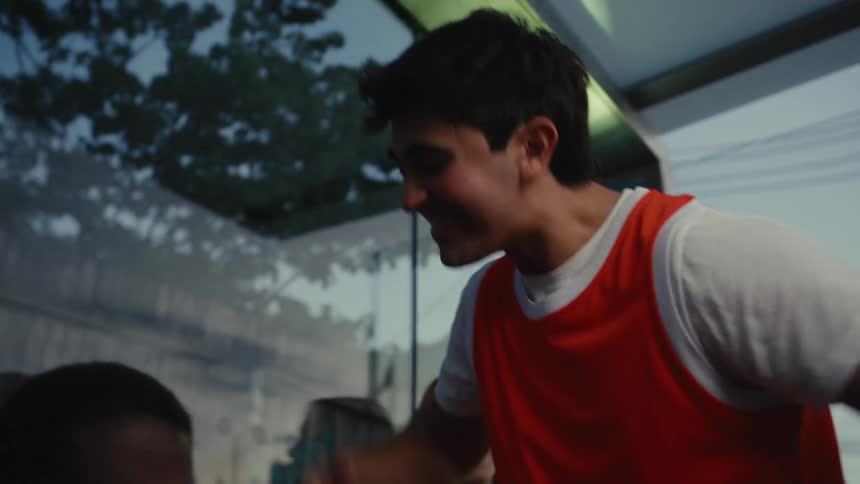 Excited friends watch a tense sports match on a mobile phone at a bus stop and celebrate a big win together in slow motion