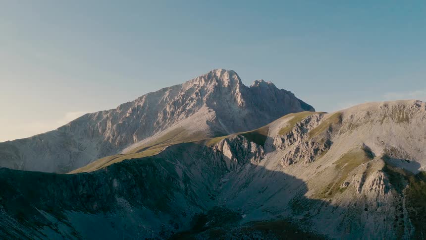 A thick blanket of fog slowly clears to reveal the majestic and rugged Gran Sasso mountain peaks at sunrise