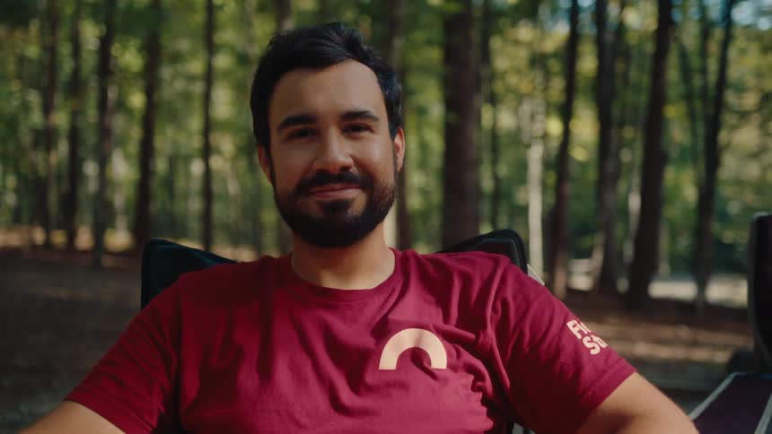 Portrait of a relaxed man with a beard enjoying a peaceful moment while camping in the woods