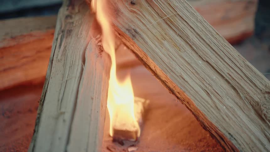 A close-up of a fire starter igniting logs for a campfire in a fire pit
