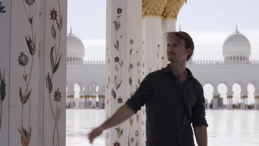 A man walks around pillars touching them