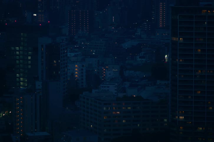 An atmospheric high-angle view of a dense city skyline with apartment buildings late at night