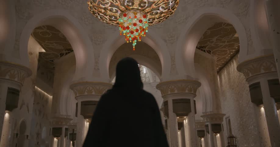 Hooded figure walks through a cathedral