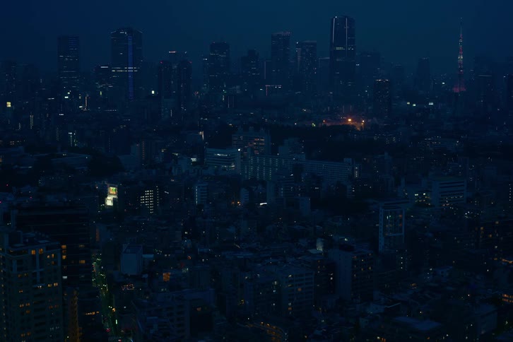 A wide aerial view of the sprawling Tokyo cityscape at night under a deep blue sky