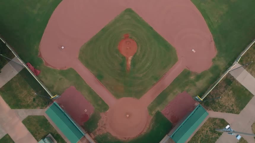 A stunning aerial shot descends over a perfectly manicured and empty baseball field