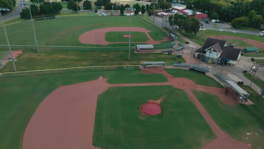 A slow aerial push-in shot over a quiet and empty baseball field complex