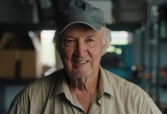 Portrait of a friendly elderly man in a cap smiling at the camera in his workshop
