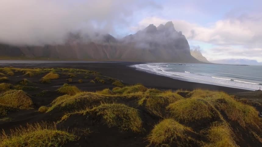 Ocean waves wash ashore a beach on a cloudy day