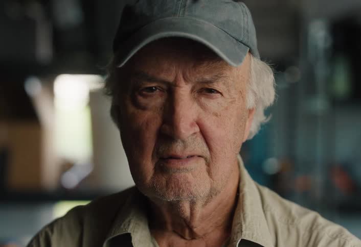 Close up portrait of a pensive elderly man in a baseball cap turning to look seriously into the camera