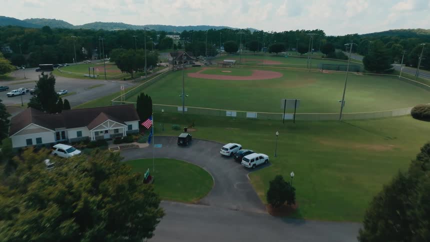 A slow aerial dolly shot reveals an empty baseball and softball sports complex on a bright sunny day