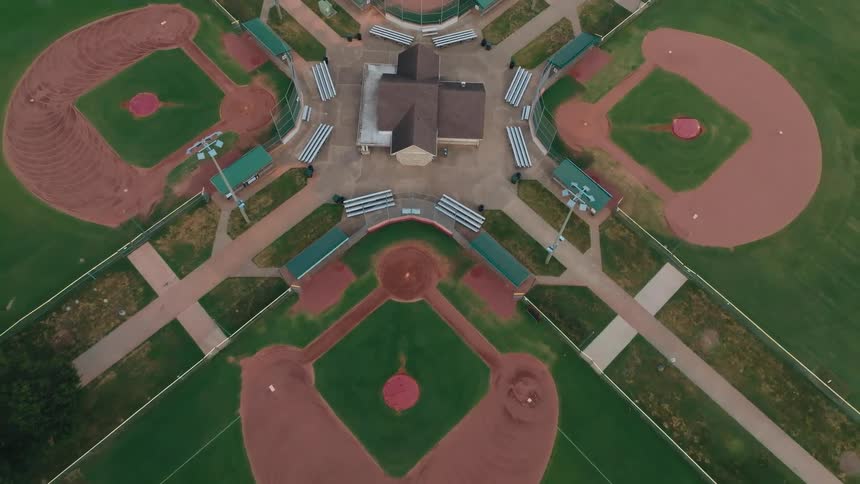 Aerial top-down shot slowly pulls back to reveal a symmetrical five-field baseball complex in a community park