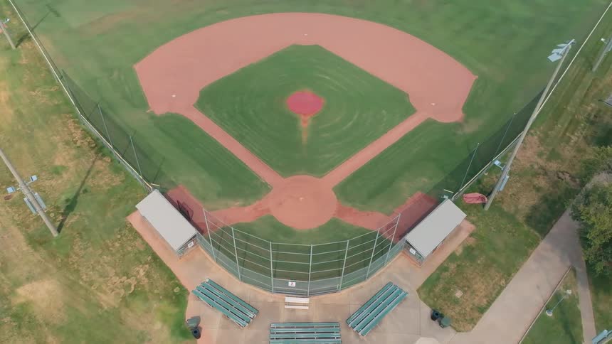An aerial view slowly lowering over a quiet and empty local baseball diamond