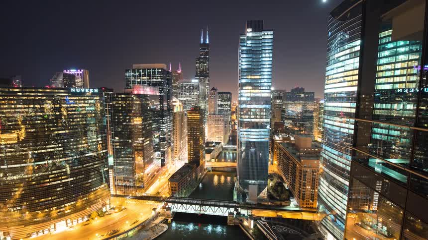 A stunning night timelapse of the vibrant Chicago skyline, featuring illuminated skyscrapers, the bustling river, and flowing traffic