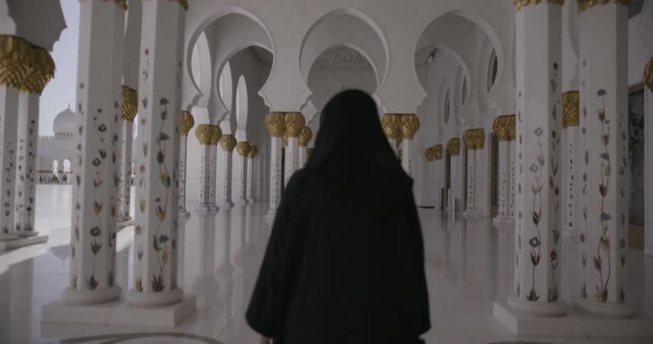 Hooded figure walks through a cathedral
