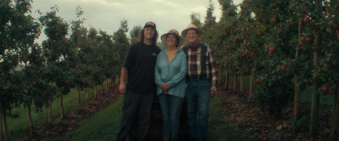 Three generations of a farming family stand proudly together in their apple orchard