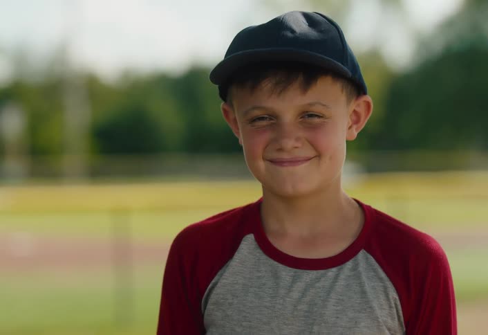 Portrait of a smiling young boy in a baseball cap on a baseball field
