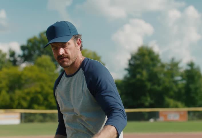 Slow motion shot of a smiling man with a mustache playing catch on a sunny baseball field