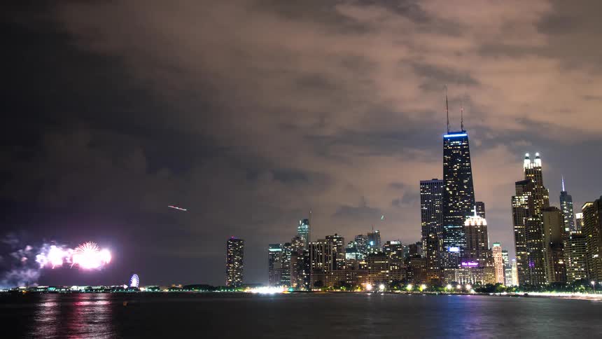 A vibrant time-lapse captures a dazzling fireworks display over the Chicago skyline and Navy Pier at night