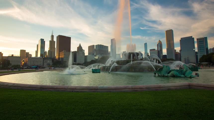 Stunning time-lapse dolly shot of Buckingham Fountain in Grant Park, Chicago, with the city skyline glowing at sunset