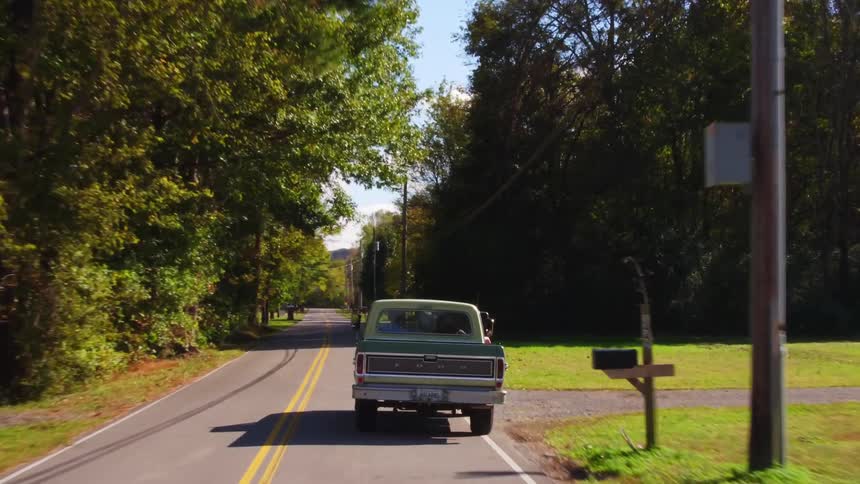 A pickup truck drives down the road on a sunny day