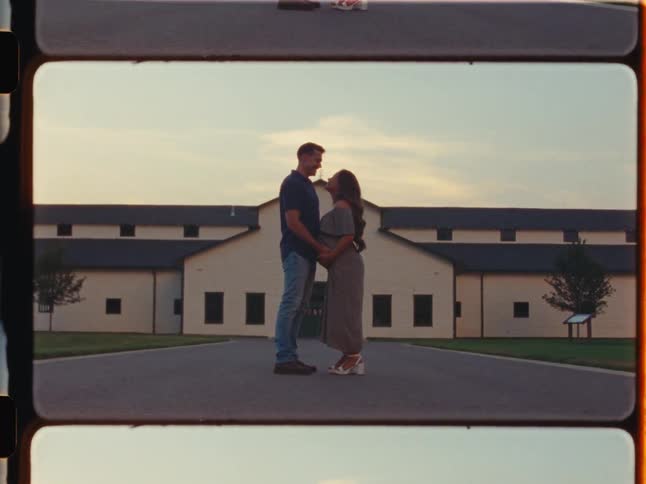 Vintage super 8 film of an expectant couple sharing a loving kiss while holding the baby bump outdoors