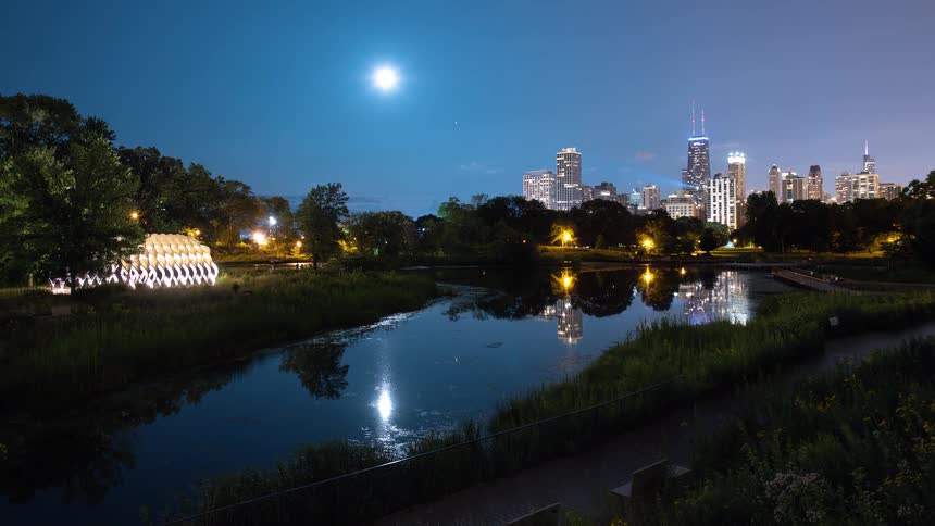A stunning night timelapse of the Chicago skyline reflecting in the tranquil waters of Lincoln Park's South Pond under a bright moon