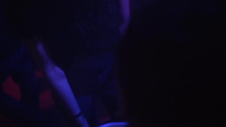 A close-up, high-angle view captures the energetic movements of people dancing in a dark club with flashing colored lights