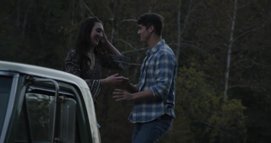 A woman helps a man get up on a truck