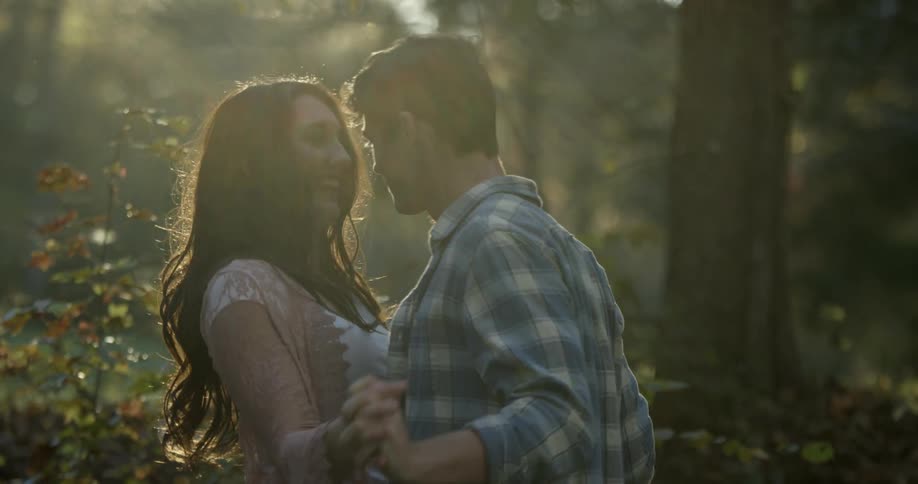 A man and woman hold hands and embrace on a sunny day