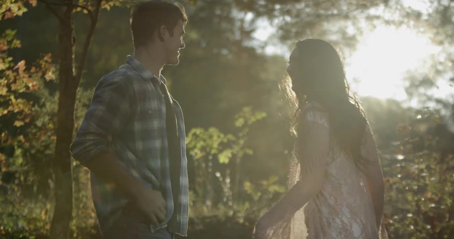 Woman and man smile in the woods on a sunny day