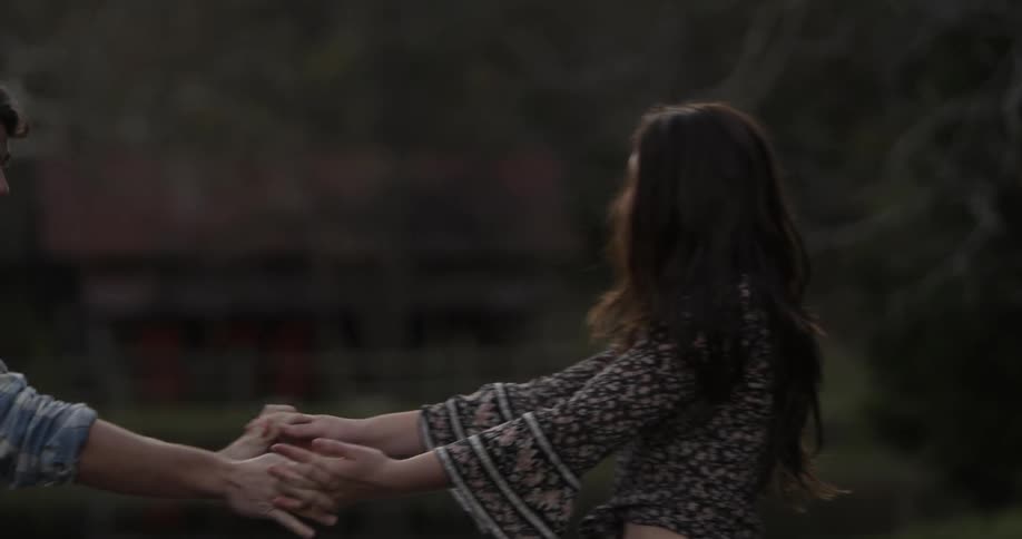 A man and woman dance outside while laughing