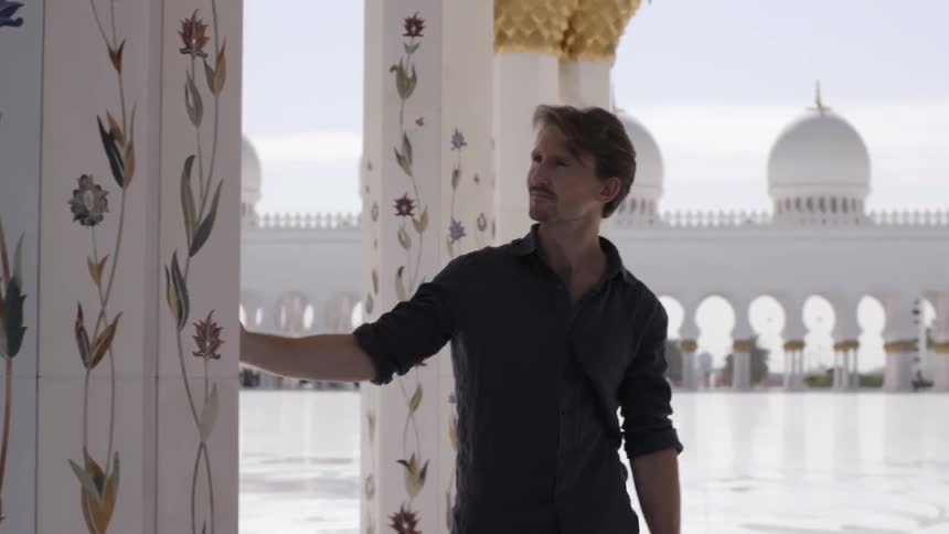 A man walks along pillars examining everything
