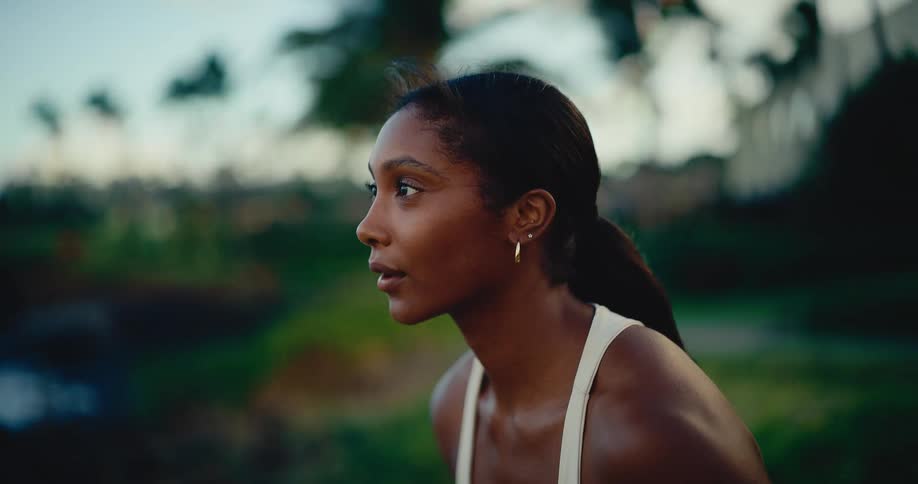 A beautiful woman stretches in a yoga pose on a tropical coastline at sunset in slow motion