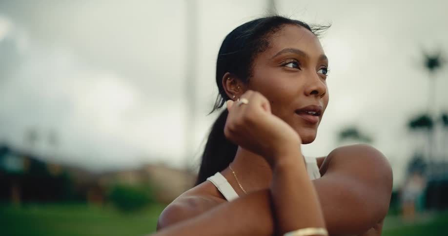 A beautiful woman in athletic wear peacefully stretches her arms outdoors in slow motion