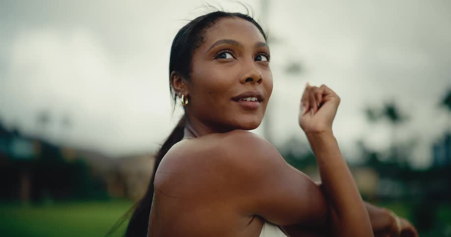 Slow motion close-up of a beautiful woman stretching her arms while warming up for a workout in a park