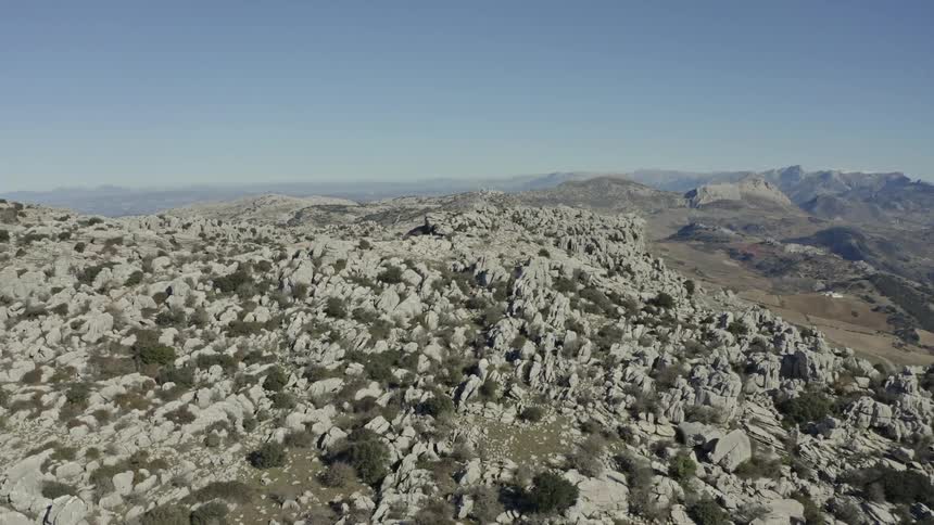A slow aerial pan over the unique and rugged karst rock formations of a mountainous region on a clear sunny day
