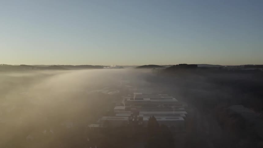 A serene aerial view of an industrial area enveloped in a blanket of fog during a beautiful sunrise