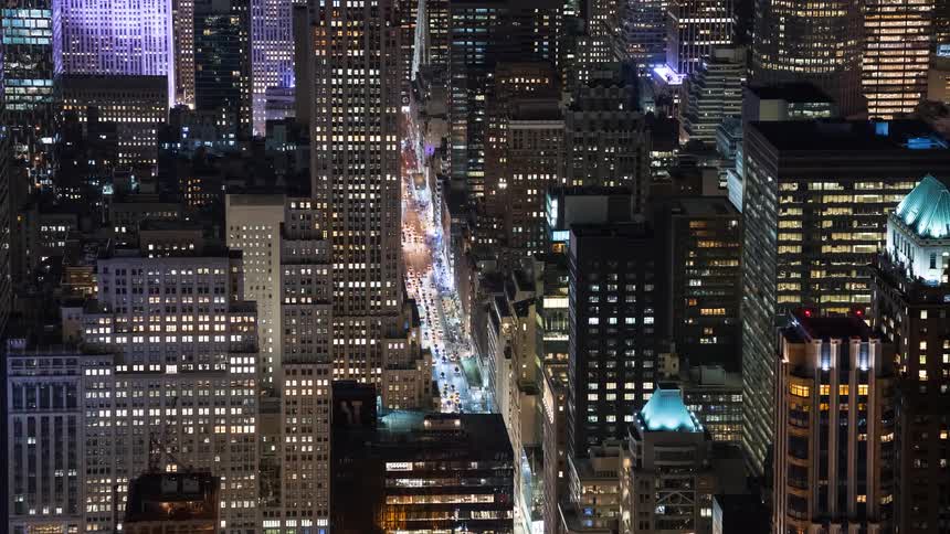 A stunning night timelapse from a high angle view of a bustling street in Manhattan surrounded by towering skyscrapers