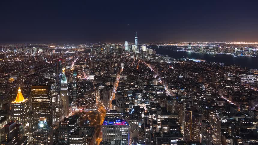 Stunning aerial night timelapse of the vibrant New York City skyline with glowing skyscrapers and streams of traffic below