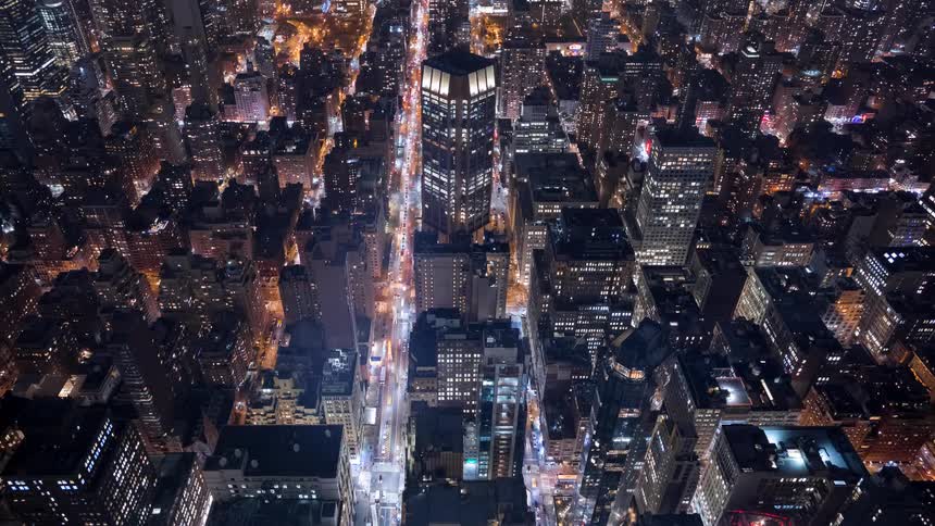 A stunning high-angle time-lapse of traffic flowing through a canyon of illuminated skyscrapers in New York City at night