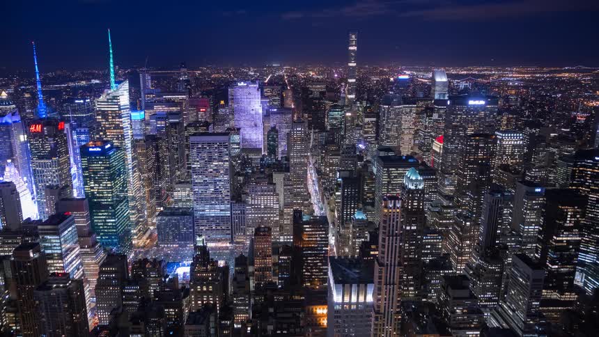 A high-angle time-lapse captures the dazzling lights of the Manhattan skyline and bustling streets at night