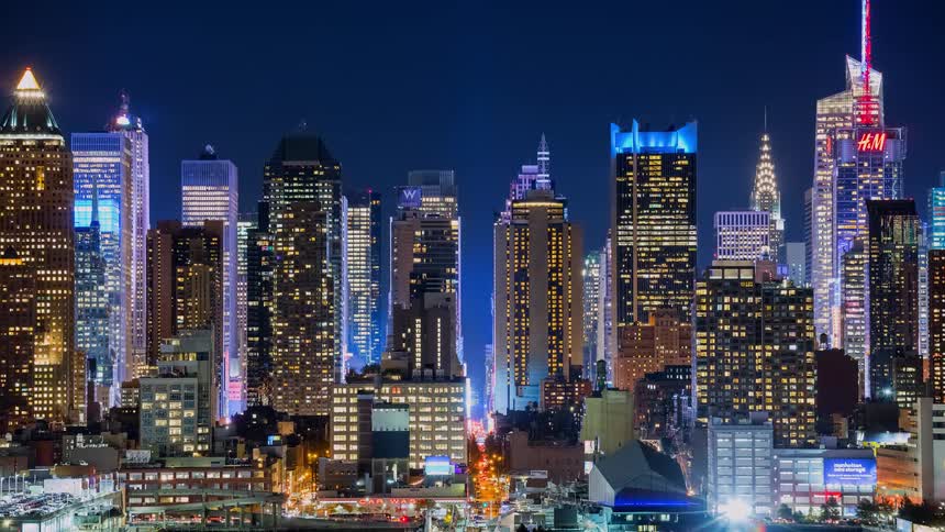 A stunning timelapse cinemagraph of the brightly lit New York City skyline with bustling traffic below at night