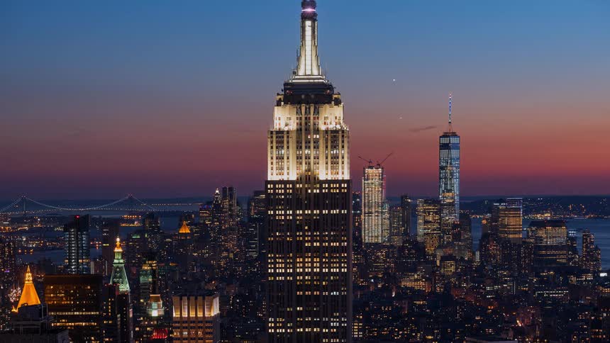 A stunning day-to-night timelapse of the iconic Empire State Building and the sprawling New York City skyline as the city lights illuminate the evening