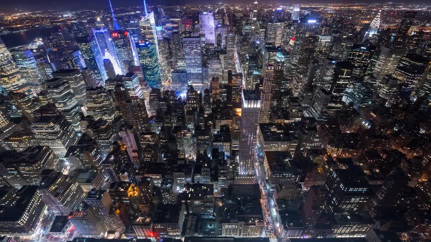 Aerial time-lapse cinemagraph of the bustling New York City skyline at night, capturing the constant flow of traffic and vibrant city lights