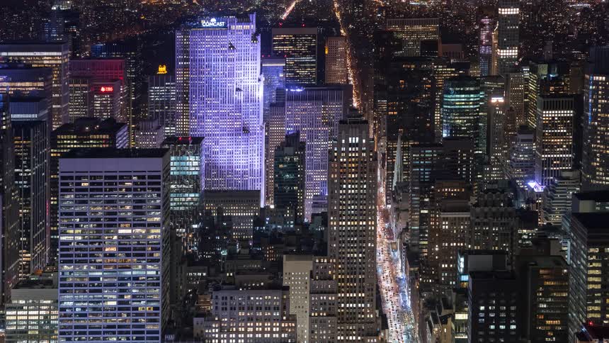A dazzling aerial time-lapse captures the vibrant energy of a metropolis at night, with glowing traffic streaming between illuminated skyscrapers