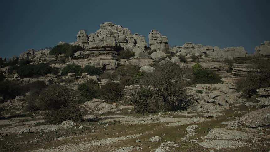 A static wide shot of the unique karst rock formations at El Torcal de Antequera in Spain under a clear blue sky