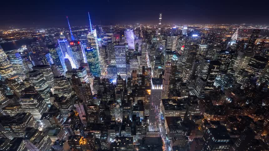 An expansive aerial cinemagraph showcases the dazzling lights of Midtown Manhattan and Times Square under a dark night sky
